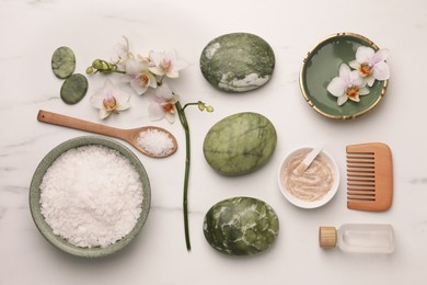 Flat lay composition with different spa products and flowers on white marble table