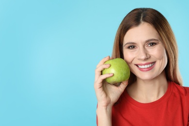 Smiling woman with perfect teeth and green apple on color background. Space for text