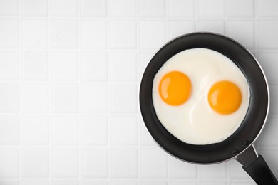 Photo of Tasty fried eggs in pan on white table, top view. Space for text