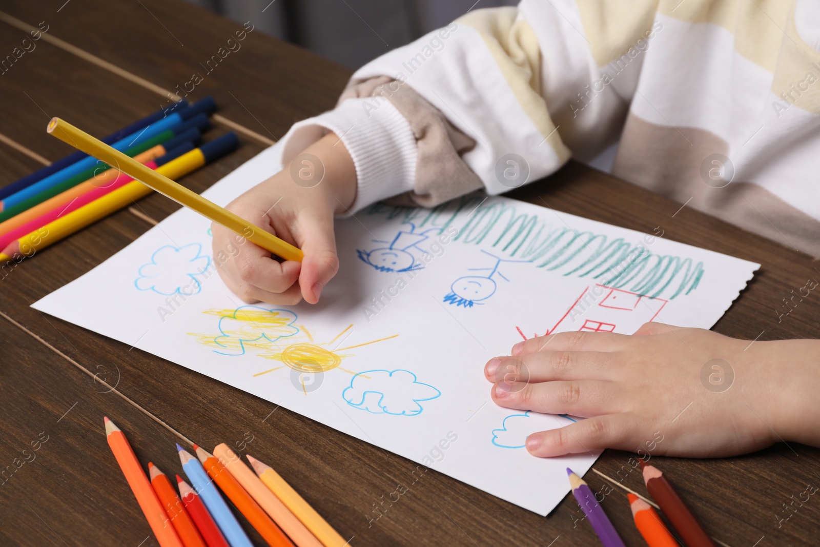 Photo of Little boy drawing with pencil at wooden table, closeup. Child`s art