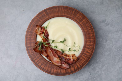 Photo of Delicious potato soup with bacon and microgreens in bowl on gray table, top view