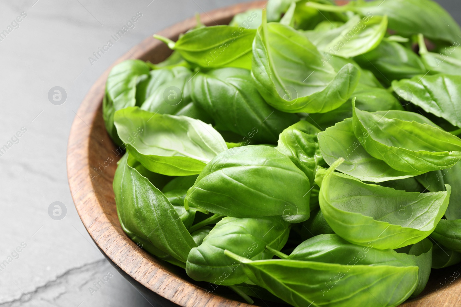 Photo of Fresh basil leaves in wooden bowl, closeup