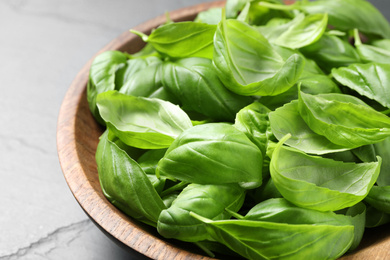 Photo of Fresh basil leaves in wooden bowl, closeup