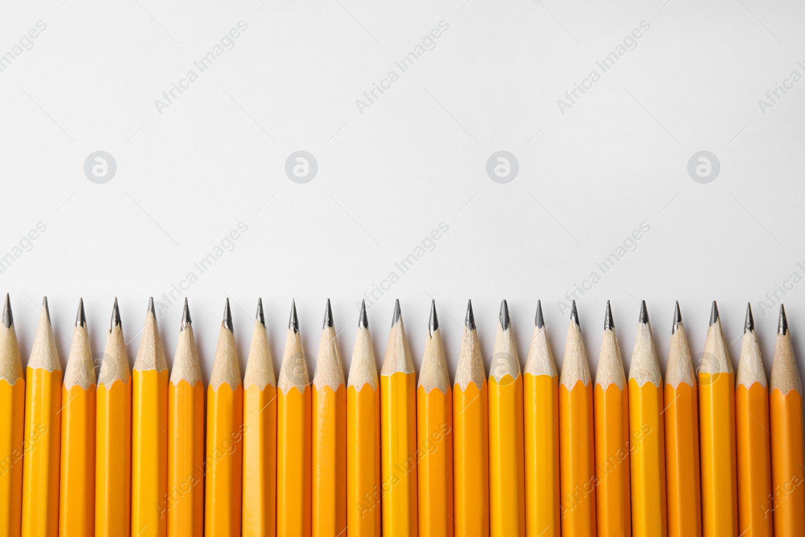 Photo of Many graphite pencils on white background, top view. Space for text