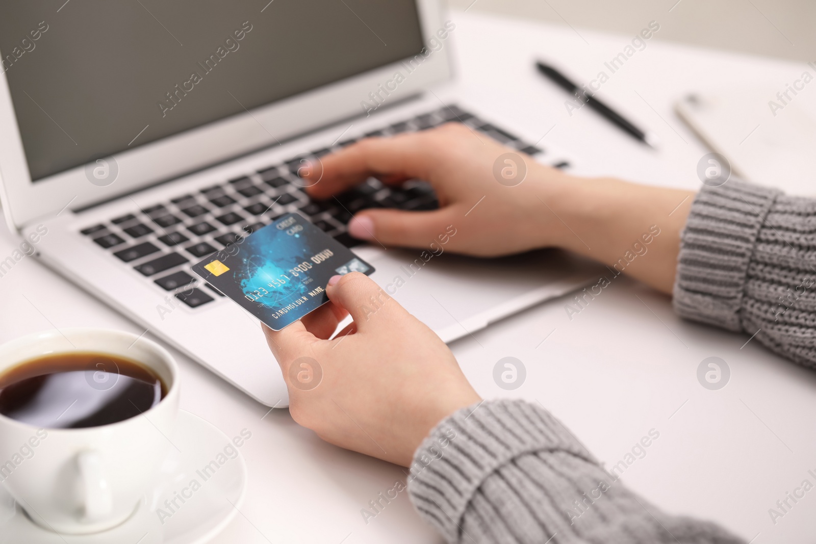 Photo of Woman with credit card using laptop for online shopping at white table, closeup