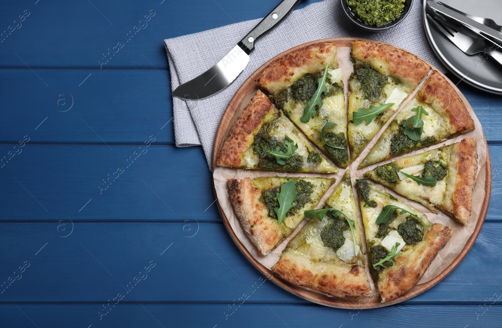 Photo of Delicious pizza with pesto, cheese and arugula served on blue wooden table, flat lay. Space for text