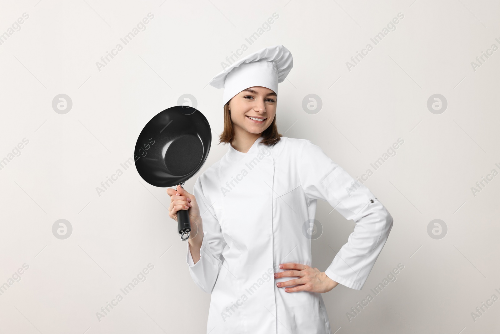 Photo of Professional chef with frying pan on light background