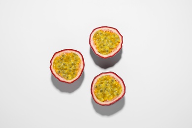 Halves of passion fruits (maracuyas) on white background, flat lay