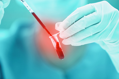 Scientist dripping blood into test tube, closeup. Laboratory analysis