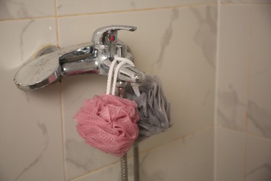 Colorful shower puffs hanging on faucet in bathroom. Space for text