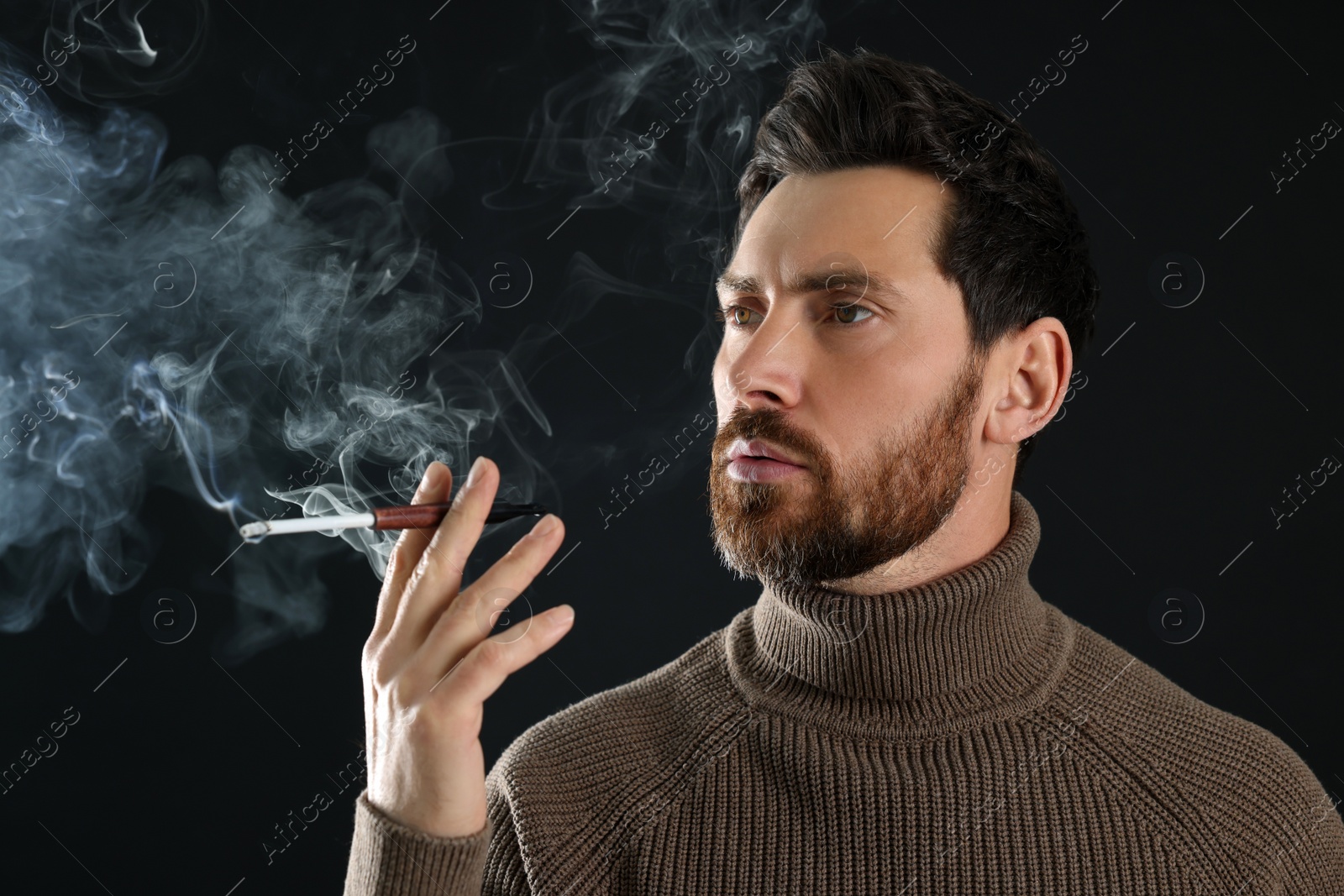 Photo of Man using cigarette holder for smoking on black background