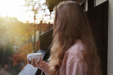 Photo of Woman enjoying cup of hot cozy drink on balcony