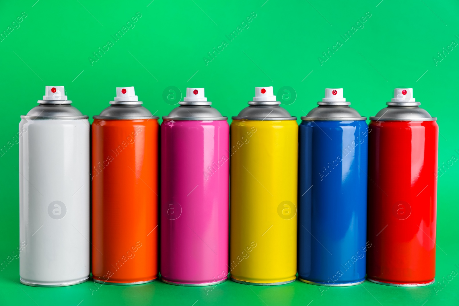 Photo of Colorful cans of spray paints on green background