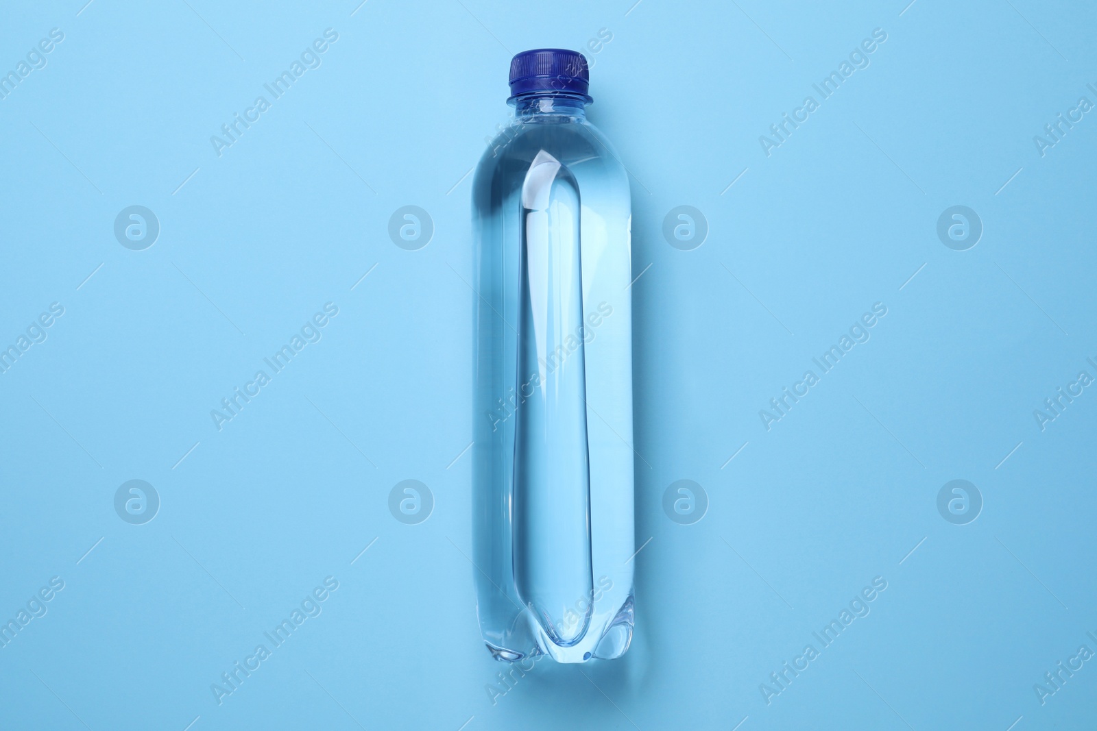 Photo of Plastic bottle with water on light blue background, top view