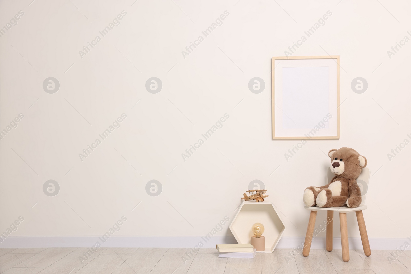 Photo of Beautiful children's room with light wall, furniture and toys, space for text. Interior design