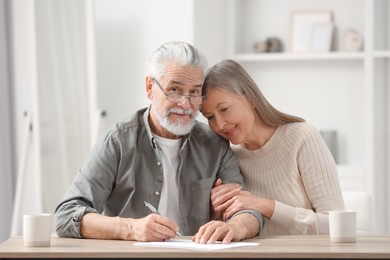 Senior couple signing Last Will and Testament indoors