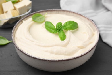 Photo of Delicious tofu sauce and basil leaves in bowl on grey table, closeup