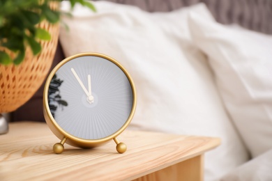 Photo of Analog alarm clock on table in bedroom. Time of day