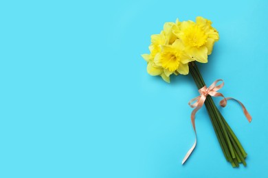 Beautiful daffodil bouquet on light blue background, top view. Space for text