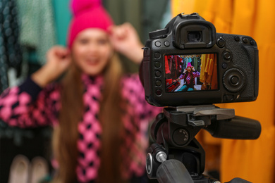 Photo of Fashion blogger recording new video in wardrobe, focus on camera