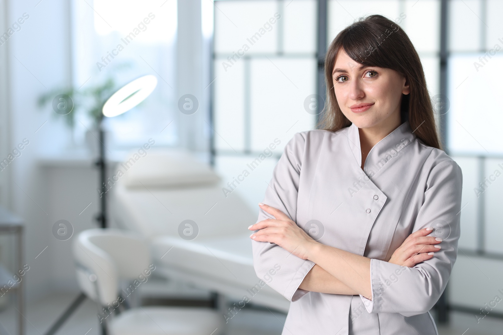 Photo of Cosmetologist in medical uniform in clinic, space for text