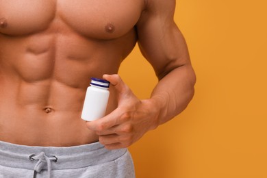 Photo of Weight loss. Athletic man with bottlesupplements on orange background, closeup. Space for text