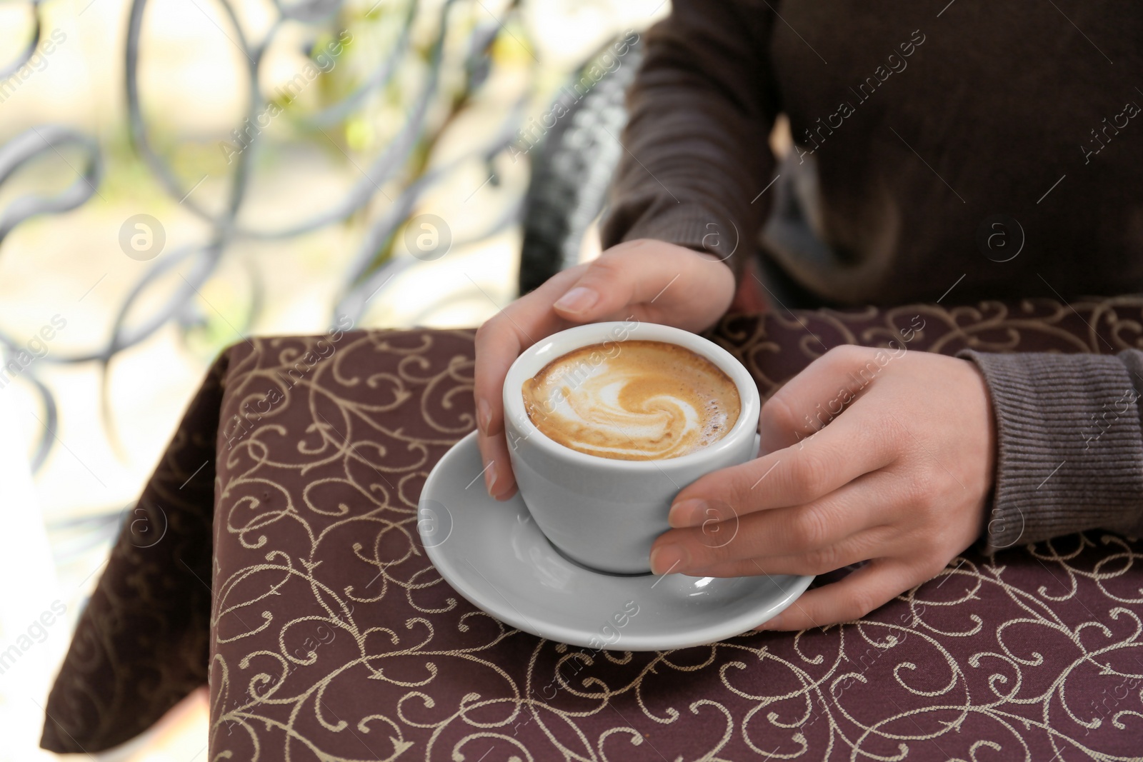 Photo of Young woman with cup of delicious coffee at table