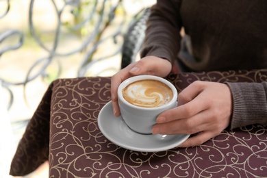 Young woman with cup of delicious coffee at table