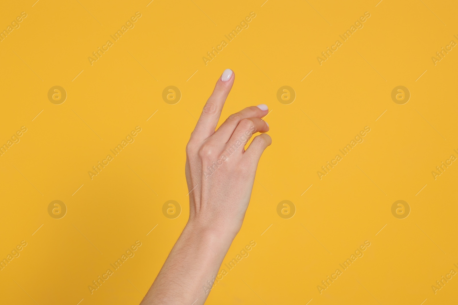 Photo of Woman holding something against yellow background, closeup on hand
