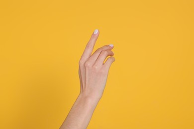 Photo of Woman holding something against yellow background, closeup on hand