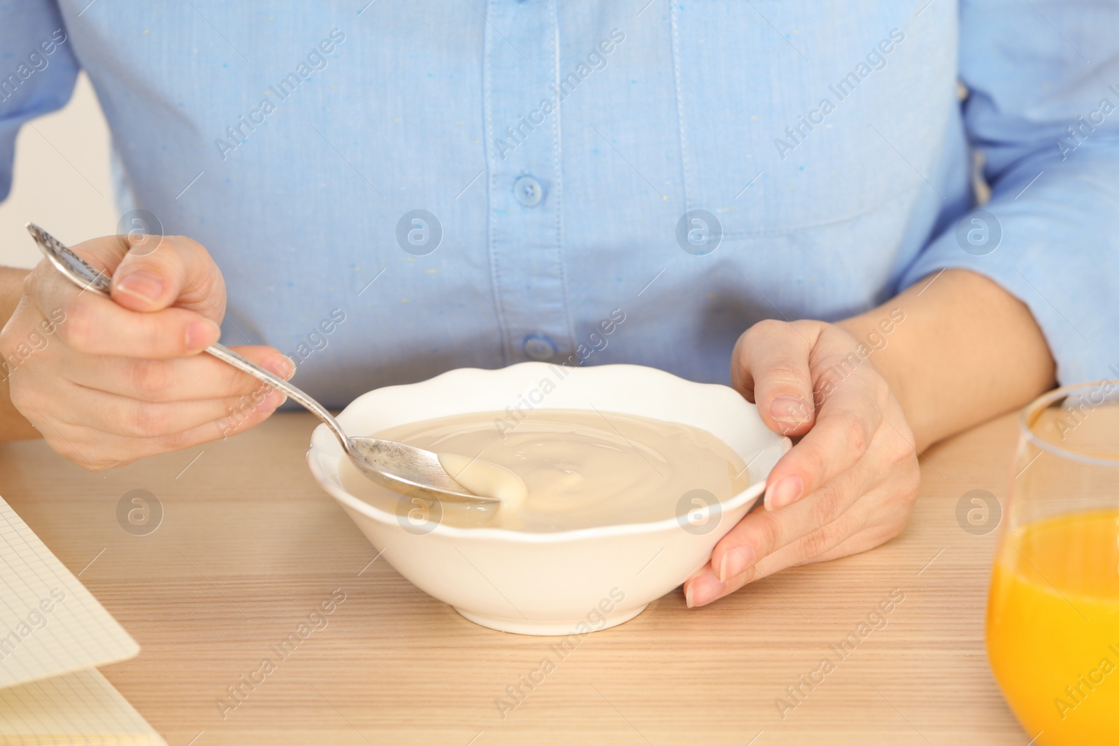 Photo of Woman with vanilla pudding at table, closeup