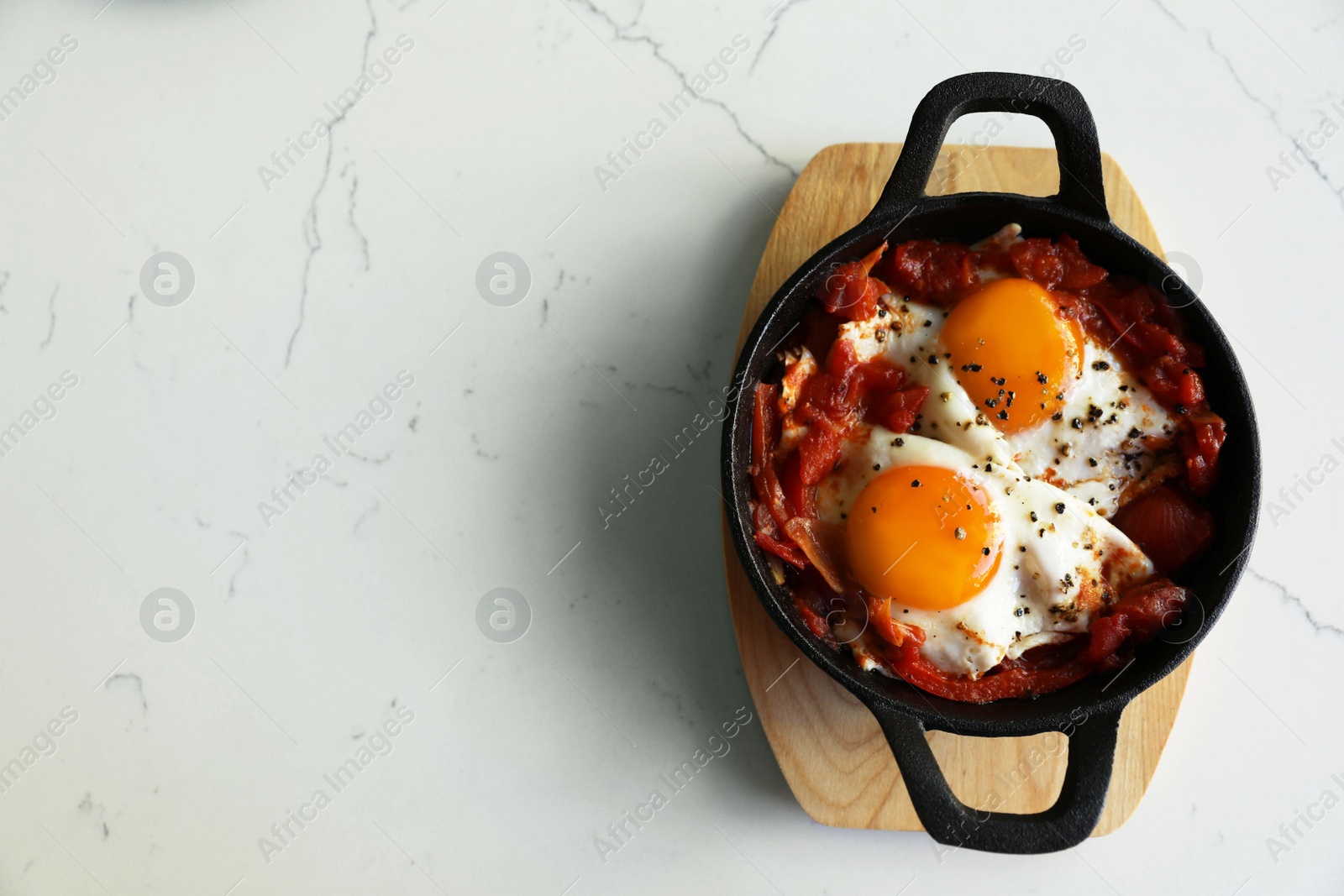 Photo of Tasty Shakshouka served on white marble table, top view. Space for text