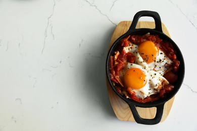 Tasty Shakshouka served on white marble table, top view. Space for text