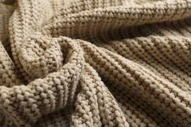 Beautiful beige knitted fabric as background, closeup