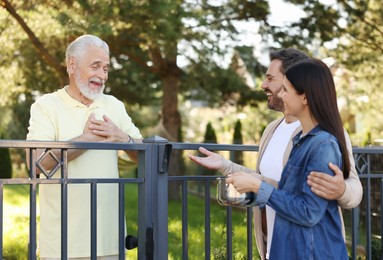 Photo of Friendly relationship with neighbours. Happy couple and senior man near fence outdoors