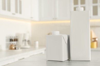 Photo of Carton boxes of milk on table in kitchen, space for text