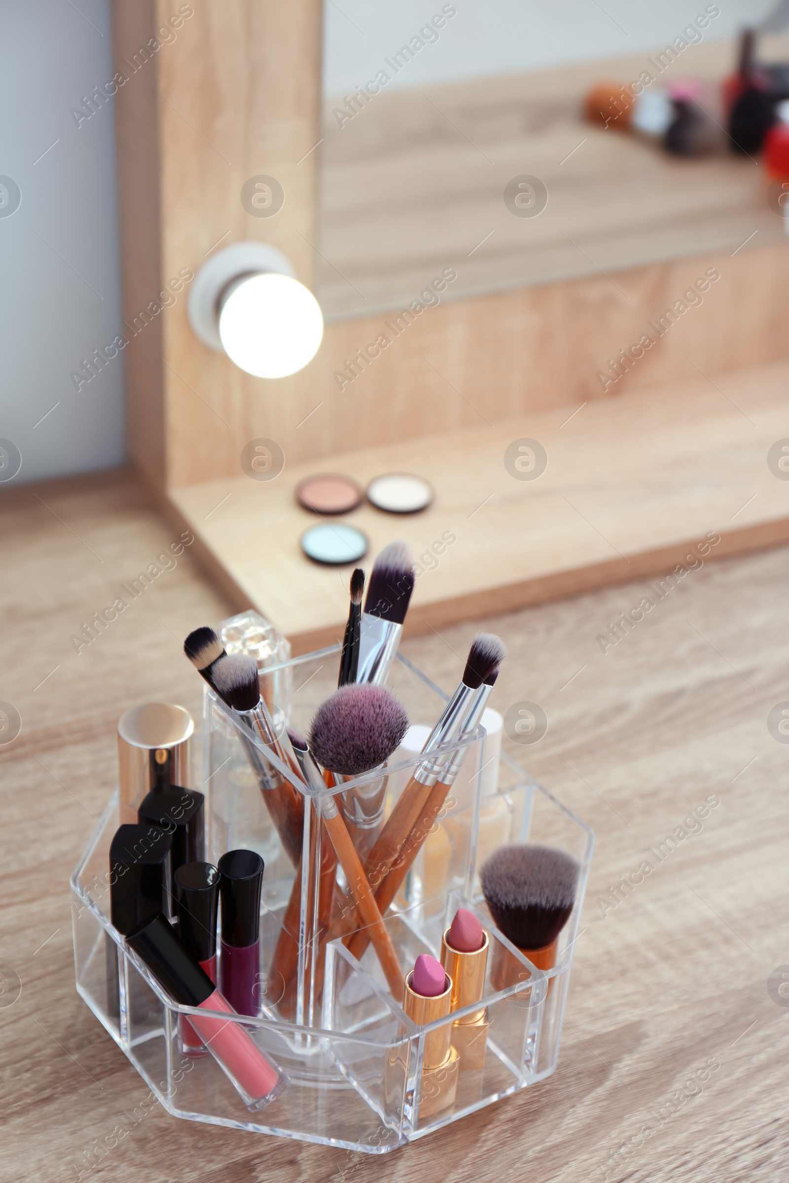 Photo of Organizer with cosmetic products for makeup on table near mirror