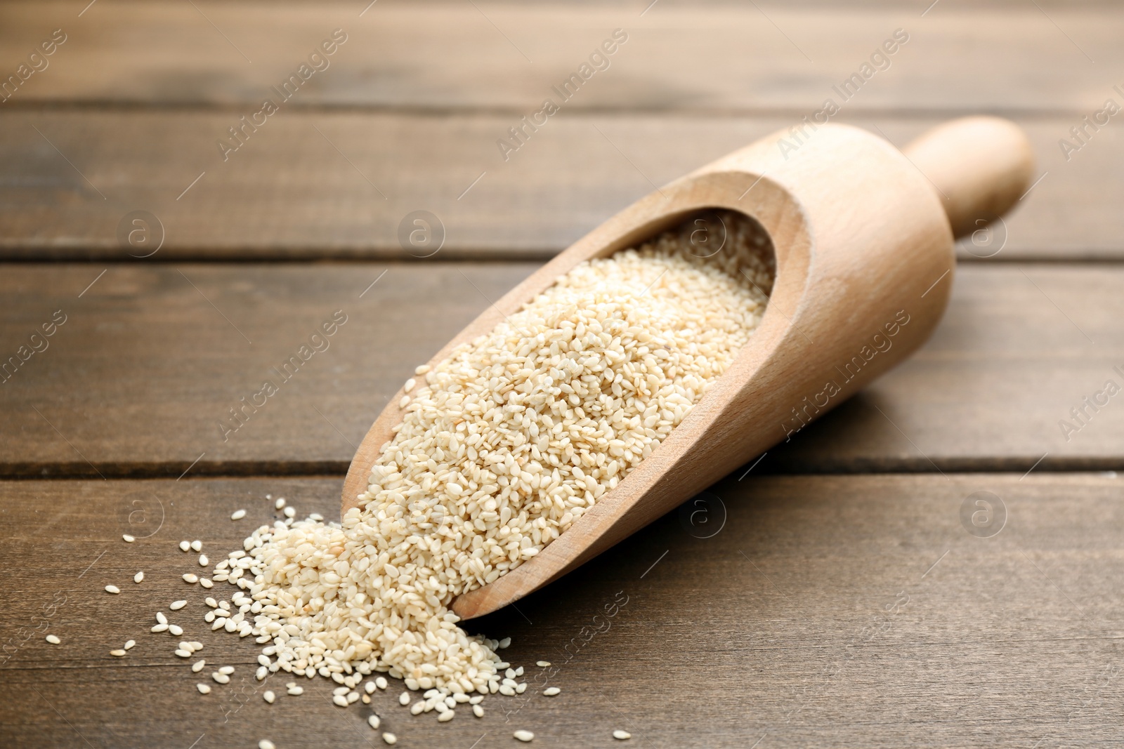 Photo of Sesame seeds in scoop on wooden table