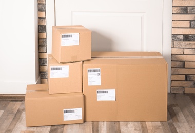 Photo of Cardboard parcel boxes on floor near apartment entrance. Mockup for design