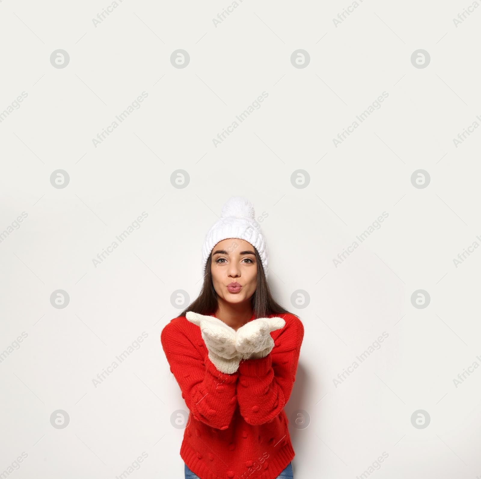 Photo of Young woman in warm sweater and hat on white background. Celebrating Christmas