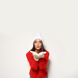 Photo of Young woman in warm sweater and hat on white background. Celebrating Christmas