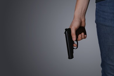 Man holding gun on dark background, closeup. Space for text