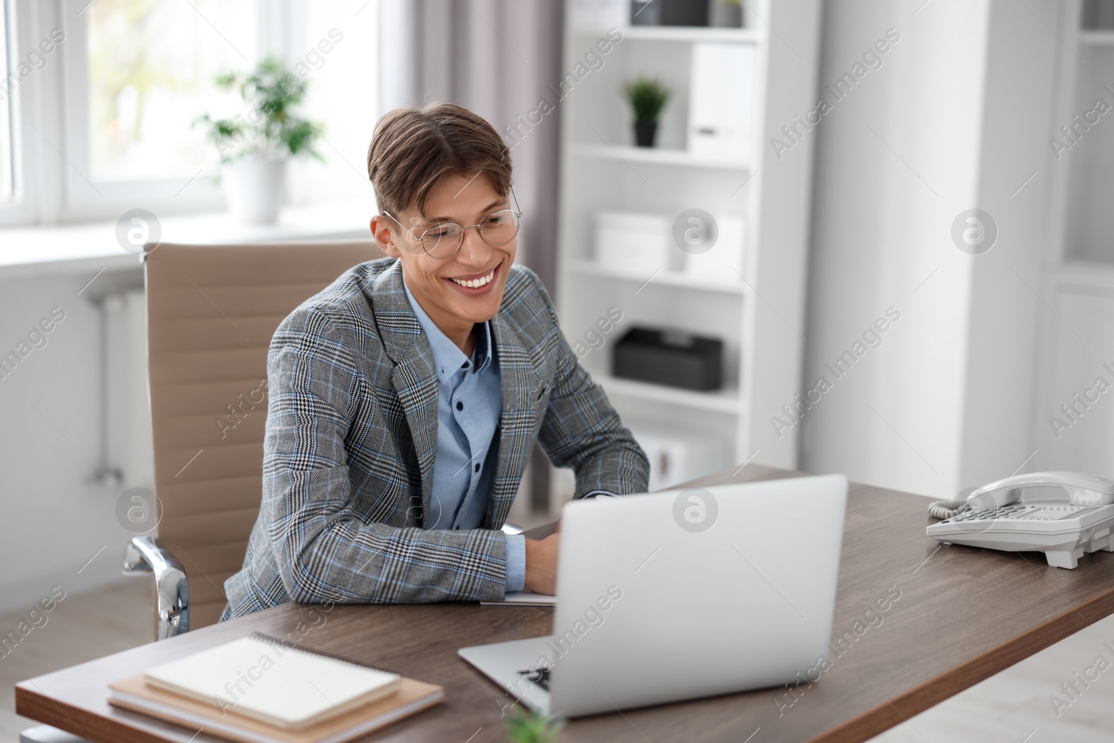 Photo of Man watching webinar at wooden table in office