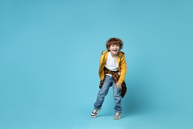 Photo of Happy little boy dancing on light blue background