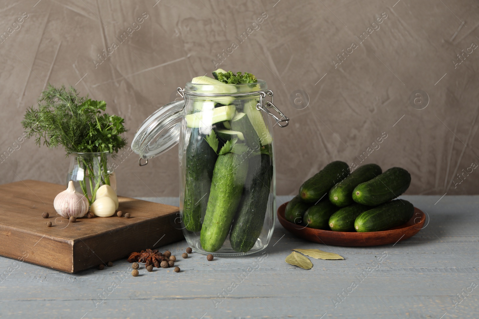 Photo of Pickling jar with fresh ripe cucumbers on grey wooden table