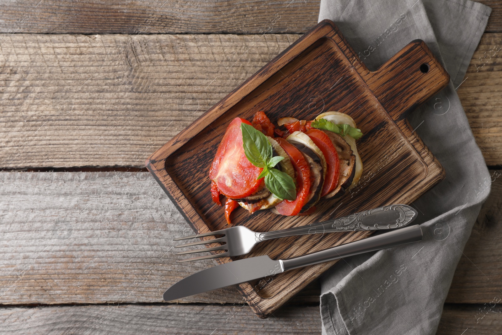 Photo of Delicious ratatouille served with basil on wooden table, top view. Space for text