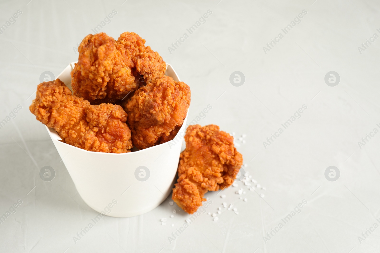 Photo of Tasty deep fried chicken pieces on white table. Space for text