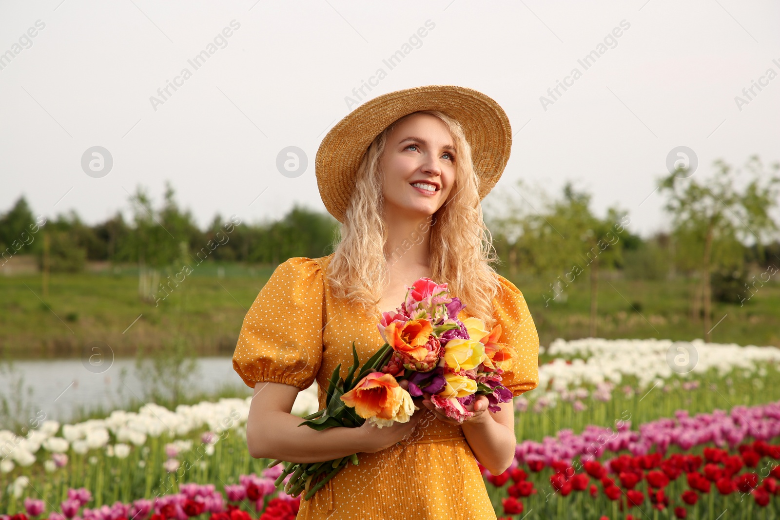 Photo of Happy woman with spring bouquet of flowers in beautiful tulip field on sunny day