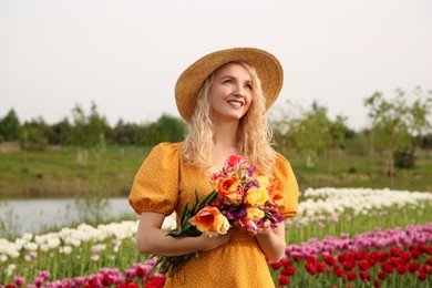 Photo of Happy woman with spring bouquet of flowers in beautiful tulip field on sunny day