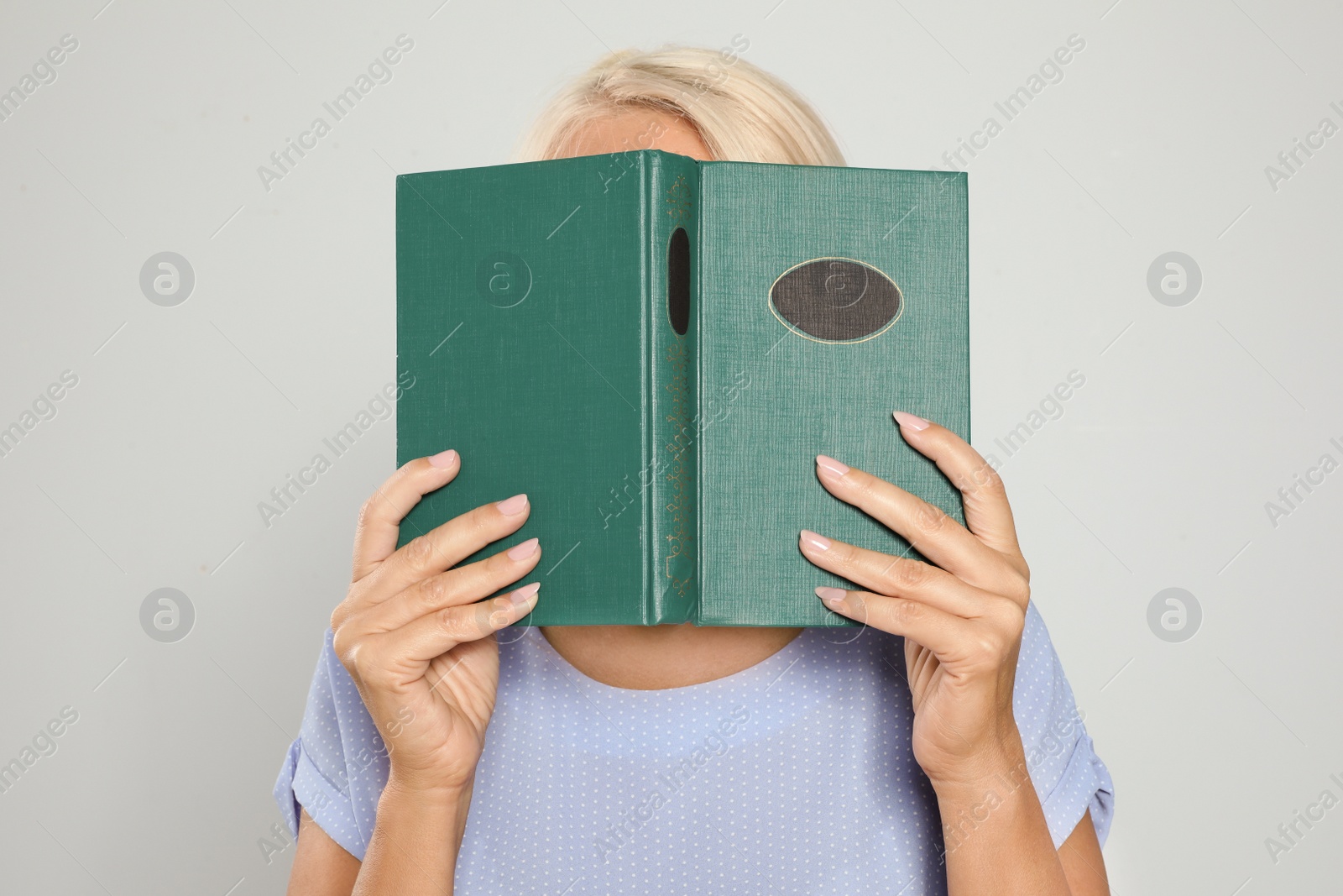 Photo of Mature woman reading book on light background